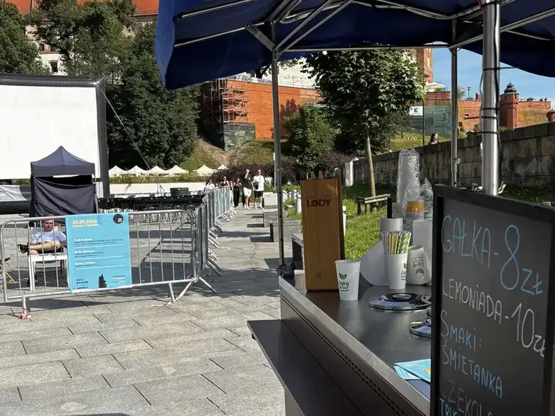 Mobilna lodziarnia z tablicą cenową na festiwalu filmowym w Krakowie pod Wawelem